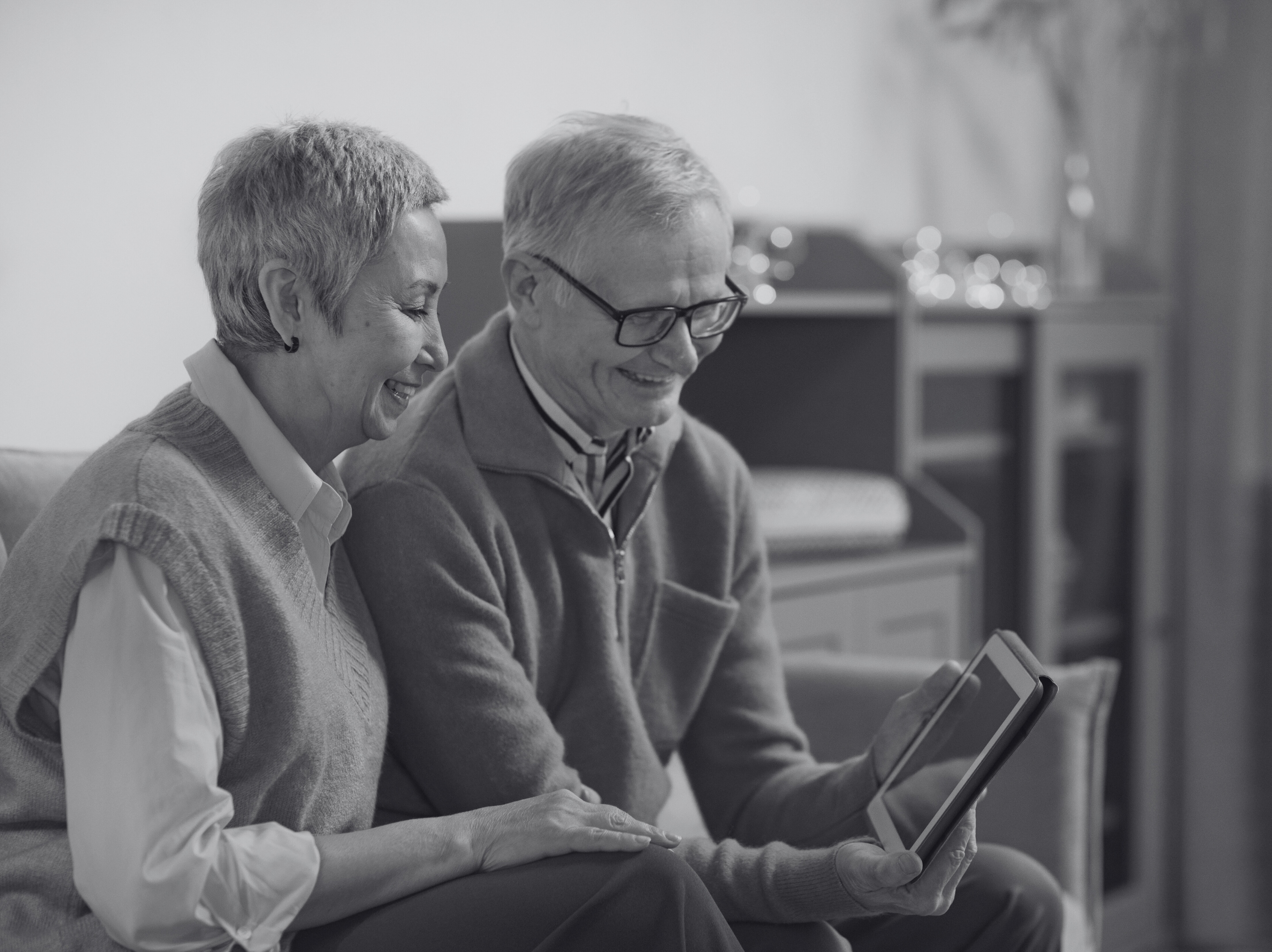 an elderly couple smiles at a book